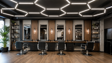 Modern barbershop with neutral-white hexagonal LED tube ceiling lights above four cutting stations