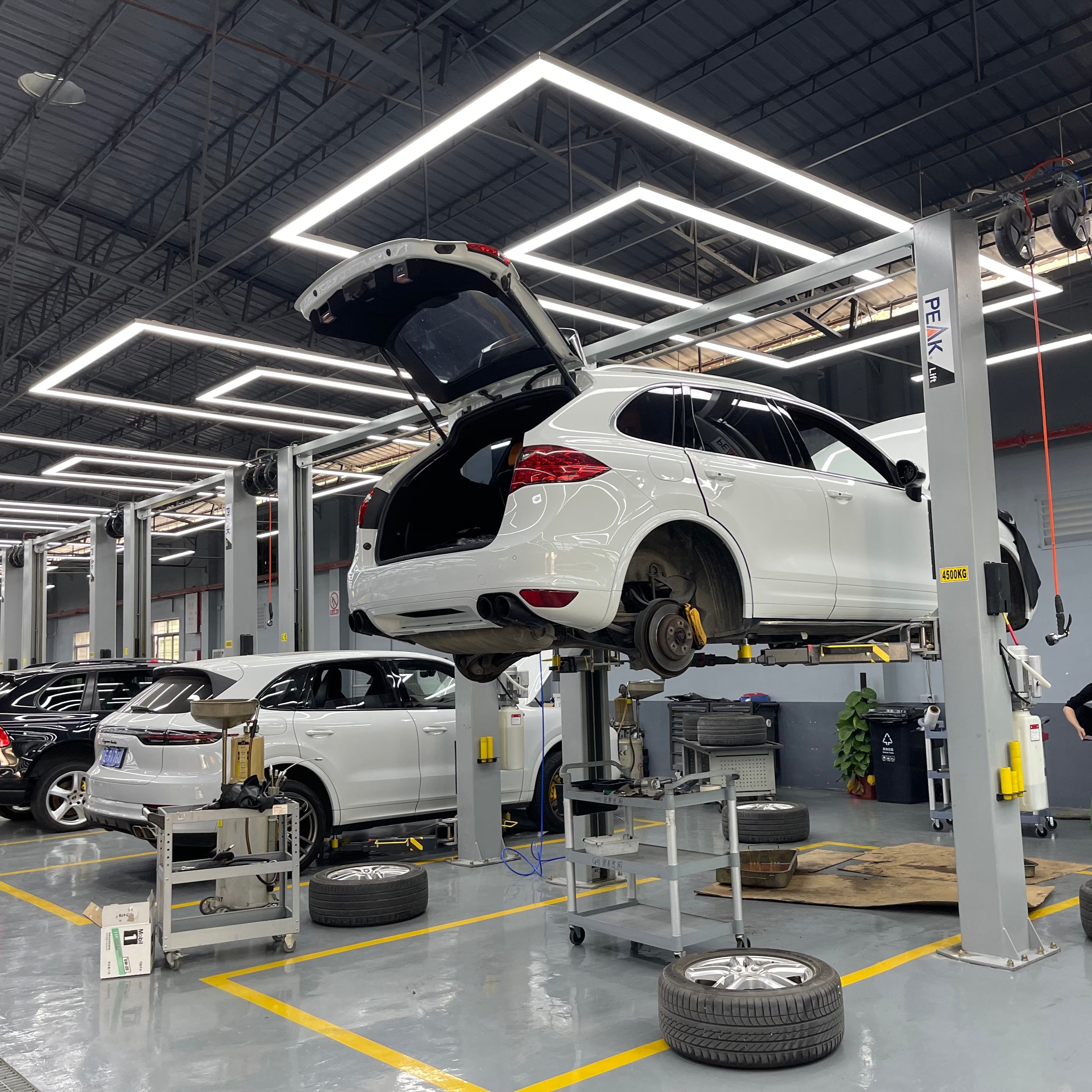 Automotive repair shop with cars on lifts and tools in a well-lit garage.
